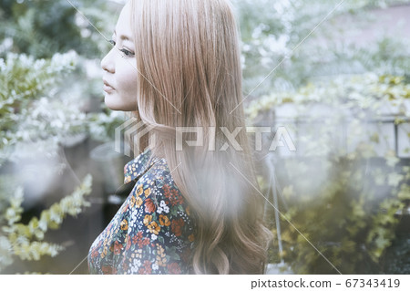一名捲髮婦女的上鏡圖片有美麗的頭髮外形和植物背景的 一名捲髮婦女的上鏡圖片有美麗的頭髮外形和植物背景的 67343419