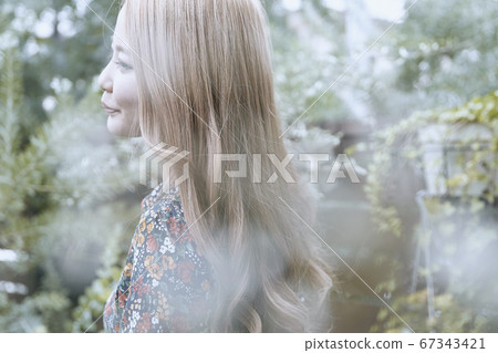 一名捲髮婦女的上鏡圖片有美麗的頭髮外形和植物背景的 67343421