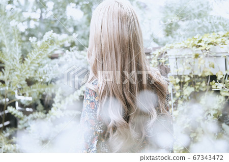 美麗的頭髮捲髮女人和植物背景上鏡的照片 67343472