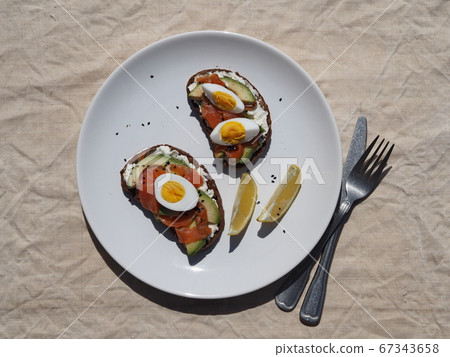 Flat lay.Sandwiches with cheese, fish and an egg in a white plate on a textile background. 67343658