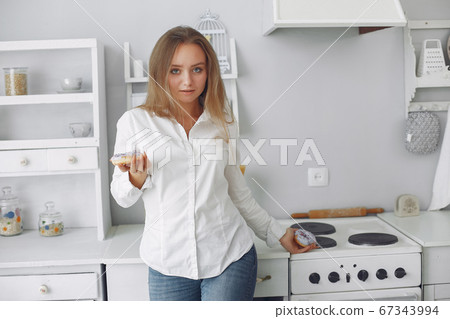 Beautiful girl standing in a kitchen with donut 67343994