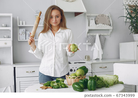 Beautiful and sporty girl in a kitchen with a vegetables 67343999