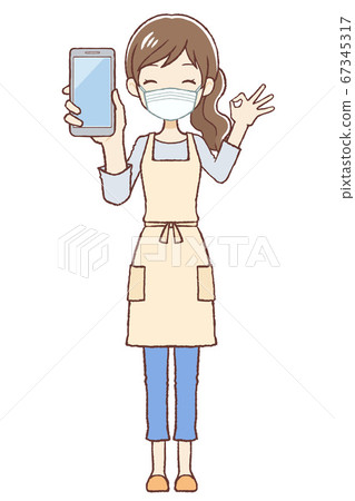 Wearing an apron female mask that gives an OK sign with a mobile phone 67345317