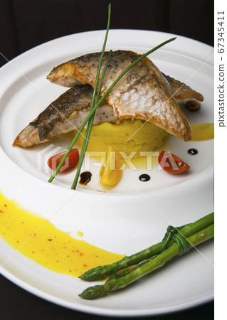 Fish fillet with sauce and vegetables on a white plate 67345411