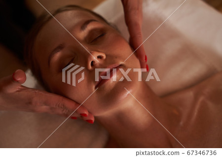 Hands of beautician touching the cheeks of young woman 67346736