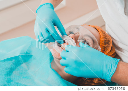 A young female dentist pulls a mouth extender at a A young female dentist pulls a mouth extender at a 67348058