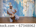 African artist in traditional clothes playing djembe drum 67348062