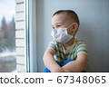 Sad little boy in medicine mask sitting near window and looking outside, quarantine at home, virus protection 67348065