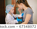 Small boy playing doctor and patient with his mother wearing a stethoscope 67348072
