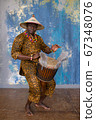Handsome african drummer weared in traditional costume playing on djembe drum 67348076