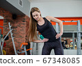 Portrait of fitness woman stretching at gym before workout. Sports activity, healthy lifestyle. Sideways lean exercise. 67348085