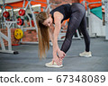 Portrait of fitness woman stretching at gym before workout. Female stretch inner thigh. Sports activity, healthy lifestyle. 67348089