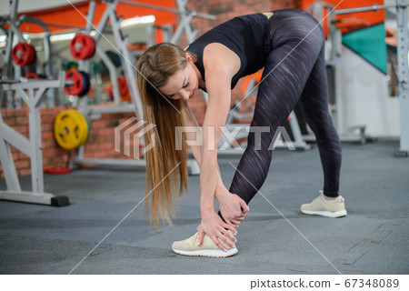Portrait of fitness woman stretching at gym before workout. Female stretch inner thigh. Sports activity, healthy lifestyle. Portrait of fitness woman stretching at gym before workout. Female stretch inner thigh. Sports activity, healthy lifestyle. 67348089