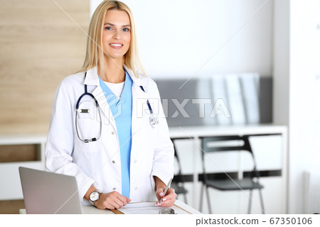 Doctor woman at work in hospital excited and happy of her profession. Blonde physician controls medication history records and exam results. Medicine and healthcare concept 67350106