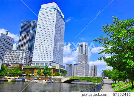 Promenade of fresh green Yokohama. Universal bridge and skyscrapers covered with ivy in Minatomirai district and houseboats moored 67352415
