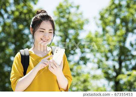 一個操作智能手機的年輕女子 一個操作智能手機的年輕女子 67355453