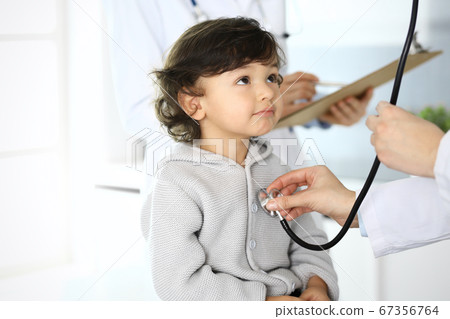 Doctor examining a child patient by stethoscope. Cute arab boy at physician appointment. Medicine and healthcare concept Doctor examining a child patient by stethoscope. Cute arab boy at physician appointment. Medicine and healthcare concept 67356764