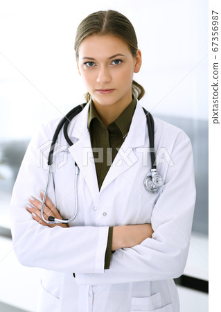 Doctor woman standing straight and looking at camera. Perfect medical service in clinic. Happy future in medicine and healthcare Doctor woman standing straight and looking at camera. Perfect medical service in clinic. Happy future in medicine and healthcare 67356987