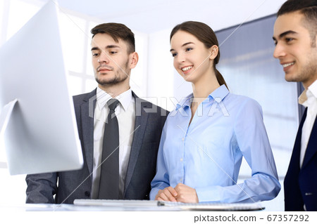 Group of diverse business people discussing questions at meeting in modern office. Colleagues working with computer at workplace. Multi ethnic teamwork and business concept Group of diverse business people discussing questions at meeting in modern office. Colleagues working with computer at workplace. Multi ethnic teamwork and business concept 67357292