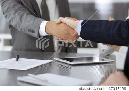 Handshake as successful negotiation ending, close-up. Unknown business people shaking hands after contract signing in modern office