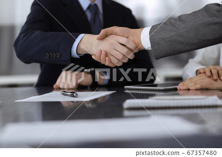 Handshake as successful negotiation ending, close-up. Unknown\
business people shaking hands after contract signing in modern\
office