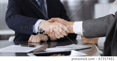 Handshake as successful negotiation ending, close-up. Unknown business people shaking hands after contract signing in modern office