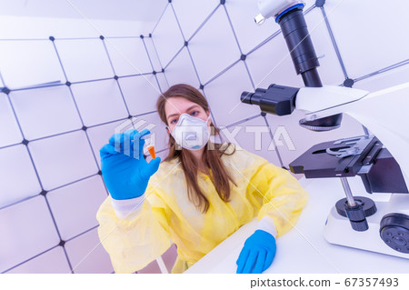 Young woman with a microtube for PCR test Young woman with a microtube for PCR test 67357493