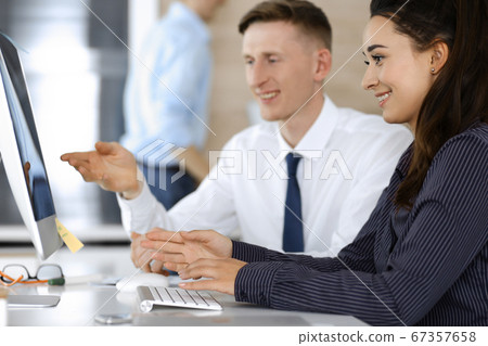 Business woman and man are discussing questions while using computer and blocknote in modern office, close-up. Teamwork in business Business woman and man are discussing questions while using computer and blocknote in modern office, close-up. Teamwork in business 67357658