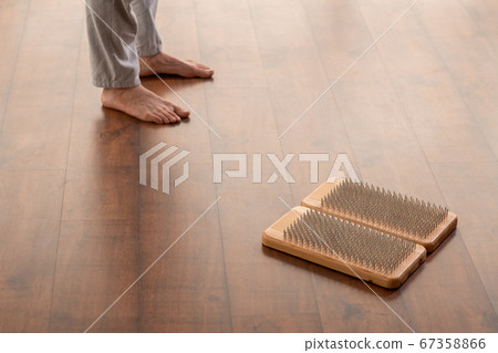 Young active barefoot man in sportspants standing on wooden floor by yoga pads Young active barefoot man in sportspants standing on wooden floor by yoga pads 67358866
