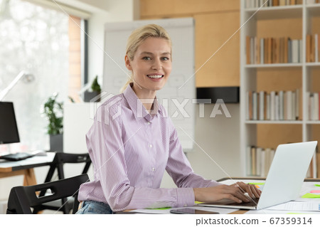 Portrait of smiling Caucasian businesswoman work on laptop in office 67359314