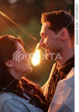 Evening light between young affectionate dates looking at one another outdoors Evening light between young affectionate dates looking at one another outdoors 67359437