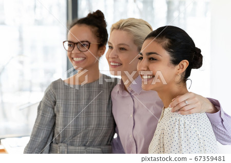 Smiling multiethnic female colleagues hug show unity at work Smiling multiethnic female colleagues hug show unity at work 67359481