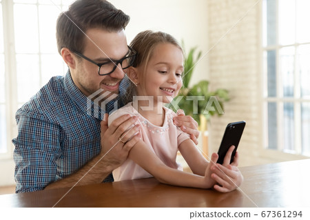 Smiling father wearing glasses hugging little daughter, taking selfie together 67361294
