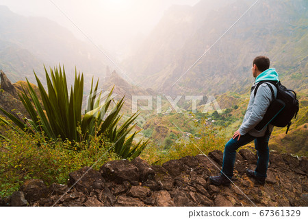Active vacation at Santo Antao Island, Cape Verde. Traveler with backpack on hike enjoying view of surreal Xo Xo valley and mountain ridge 67361329
