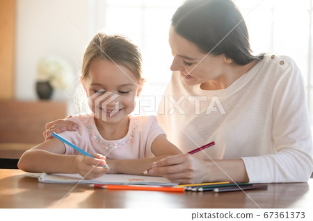 Loving smiling mother and little daughter drawing colorful pencils Loving smiling mother and little daughter drawing colorful pencils 67361373