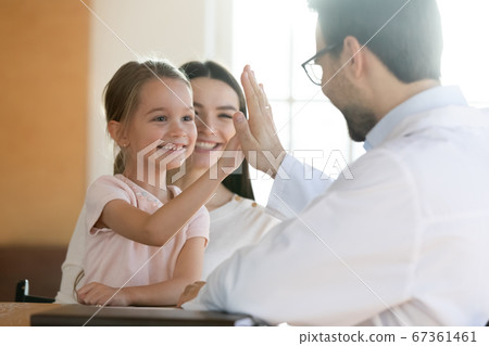 Smiling preschool girl giving high five to pediatrician at meeting 67361461