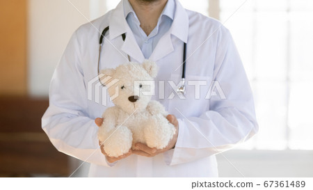 Close up male doctor holding fluffy toy, children healthcare concept Close up male doctor holding fluffy toy, children healthcare concept 67361489