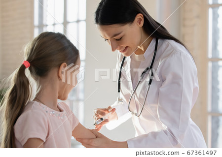 Smiling female pediatrician vaccinating little girl in hospital 67361497