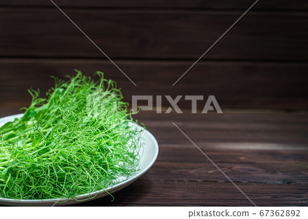fresh cutted pea microgreen sprouts on plate on wooden surface 67362892