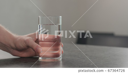 man hand takes glass of water from concrete countertop man hand takes glass of water from concrete countertop 67364726