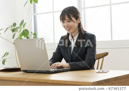 在靠窗的桌子上的筆記本電腦上打字的女商人 在靠窗的桌子上的筆記本電腦上打字的女商人 67365377