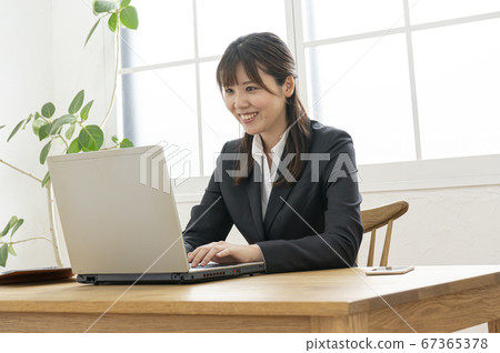 在靠窗的桌子上的筆記本電腦上打字的女商人 在靠窗的桌子上的筆記本電腦上打字的女商人 67365378