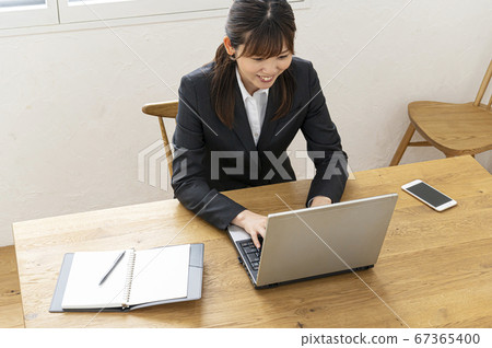Business woman typing on laptop at desk by the window 67365400