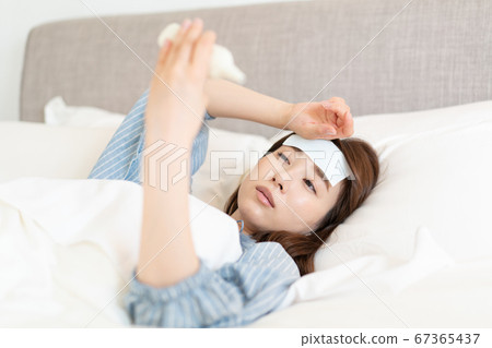 年輕女子發燒,躺在床上溫度 年輕女子發燒,躺在床上溫度 67365437