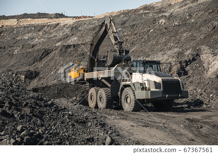 Large quarry dump truck. Loading the rock in dumper. Loading coal into body truck. Production useful minerals. Mining truck mining machinery, to transport coal from open-pit excavator work 67367561