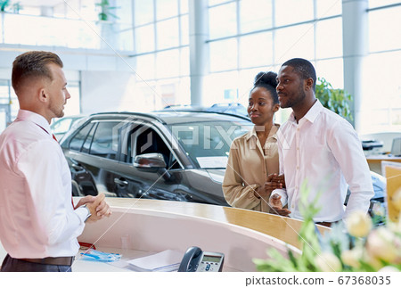 auto business. friendly manager greeting dark-skinned customers 67368035