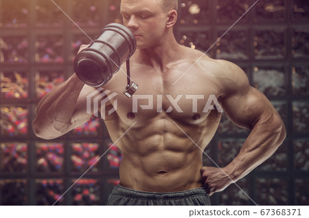 Bodybuilder drinking water after fitness workout. 67368371