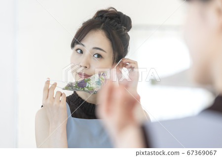 戴著花面具，看著鏡子的年輕女子 67369067