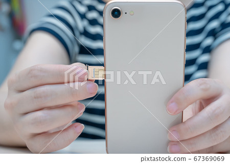 Image of inserting SIM card into smartphone and starting 67369069