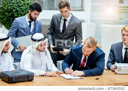 Sheikh businessman signing document Sheikh businessman signing document 67369302